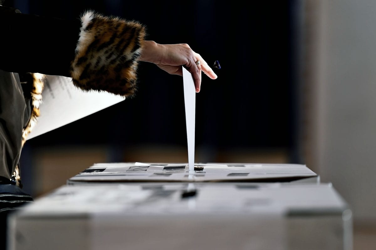 Someone casting a vote by putting their ballot in the box