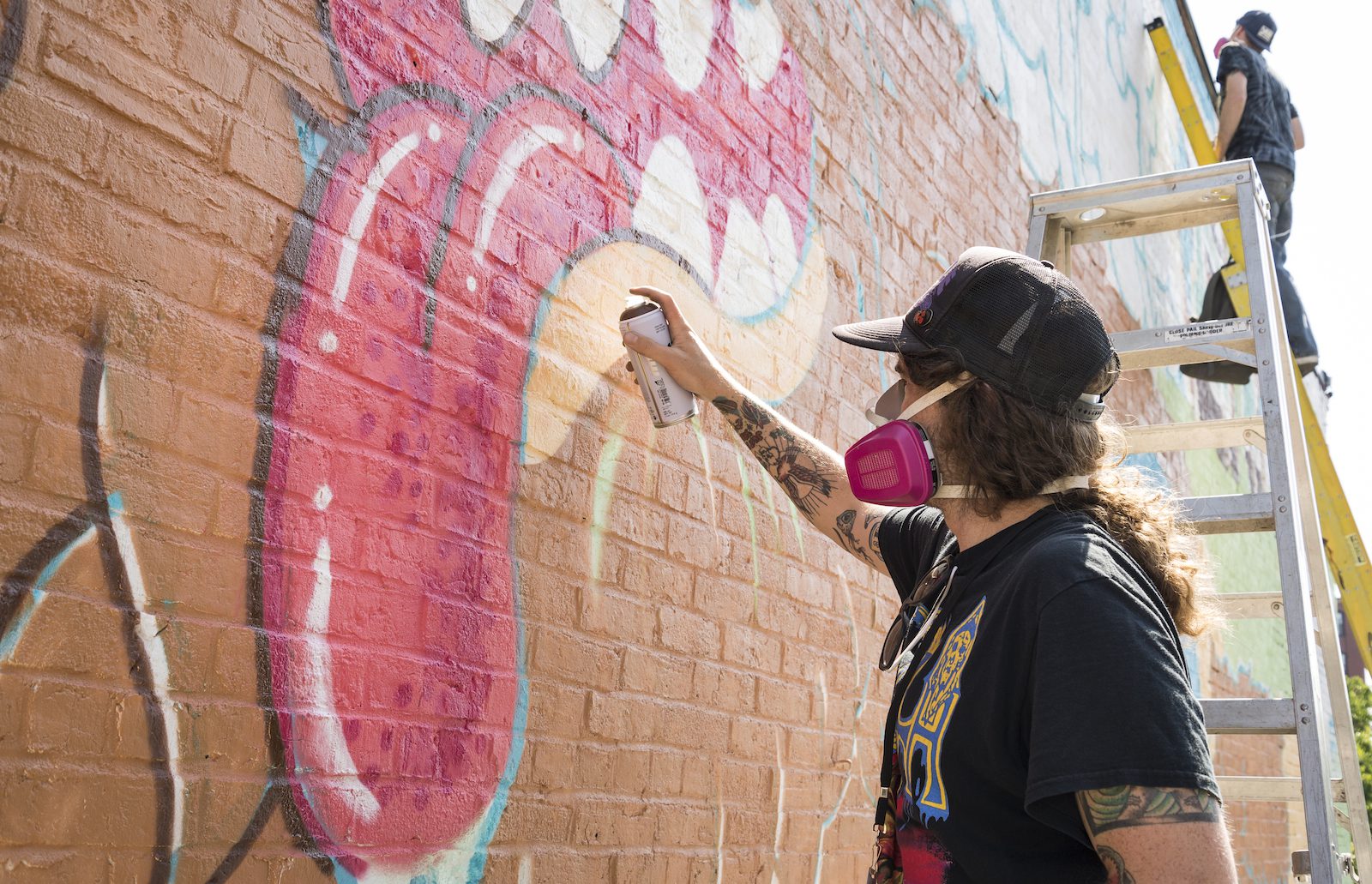 Artist Tallboy adds details to the mouth of the monster in his and Brian Denahy's mural on Washington Street.