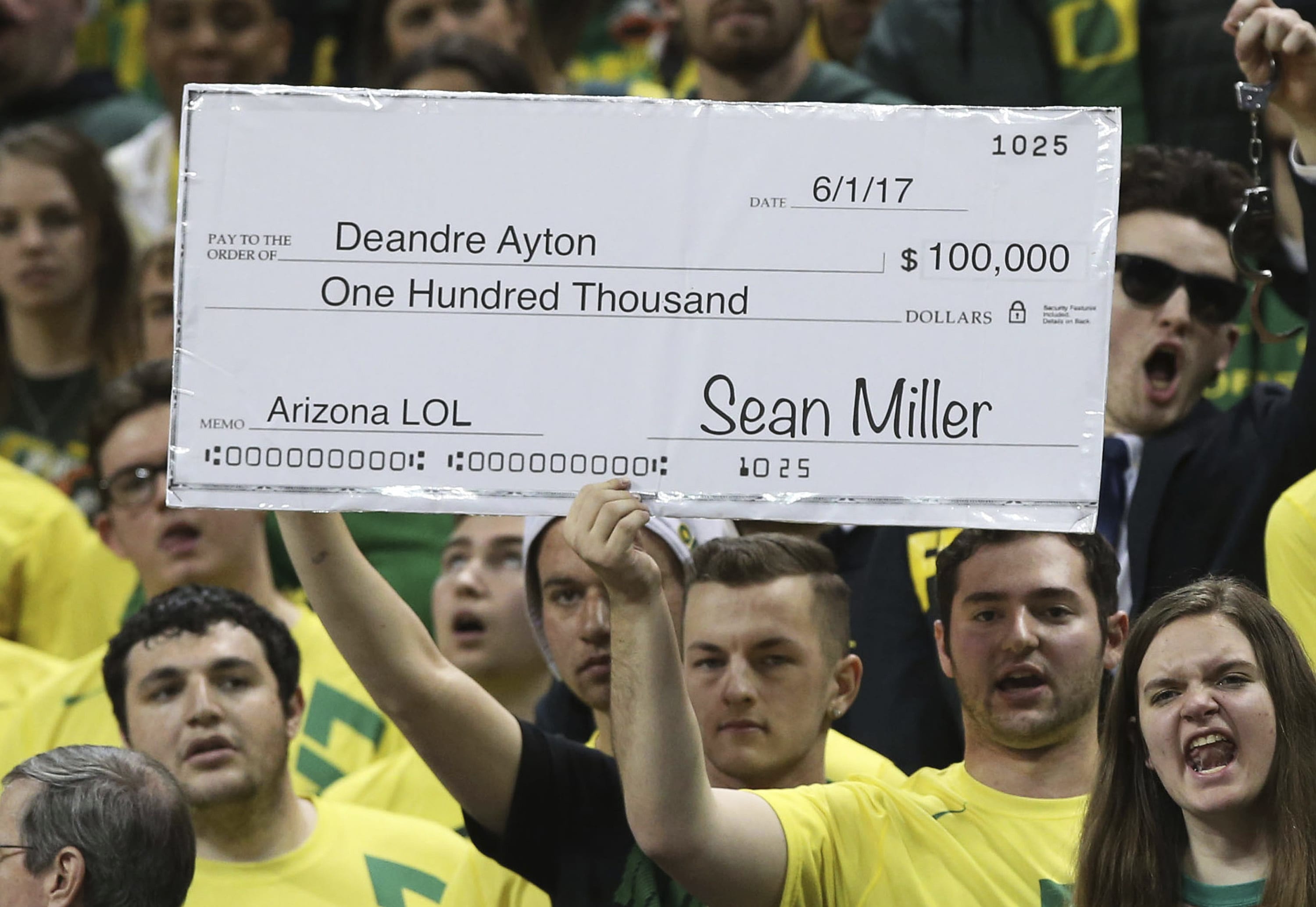 Fans in the Oregon student section hold up a sign making fun of the controversy surrounding Arizona head coach Sean Miller during the first half of an NCAA college basketball game Saturday, Feb. 24, 2018, in Eugene, Ore. (AP Photo/Chris Pietsch)