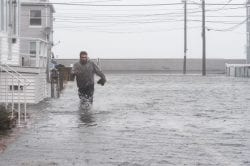 Nick Marazzi of East Boston wades through the flood waters on Pearl Avenue in Revere as he makes his way back to his truck.