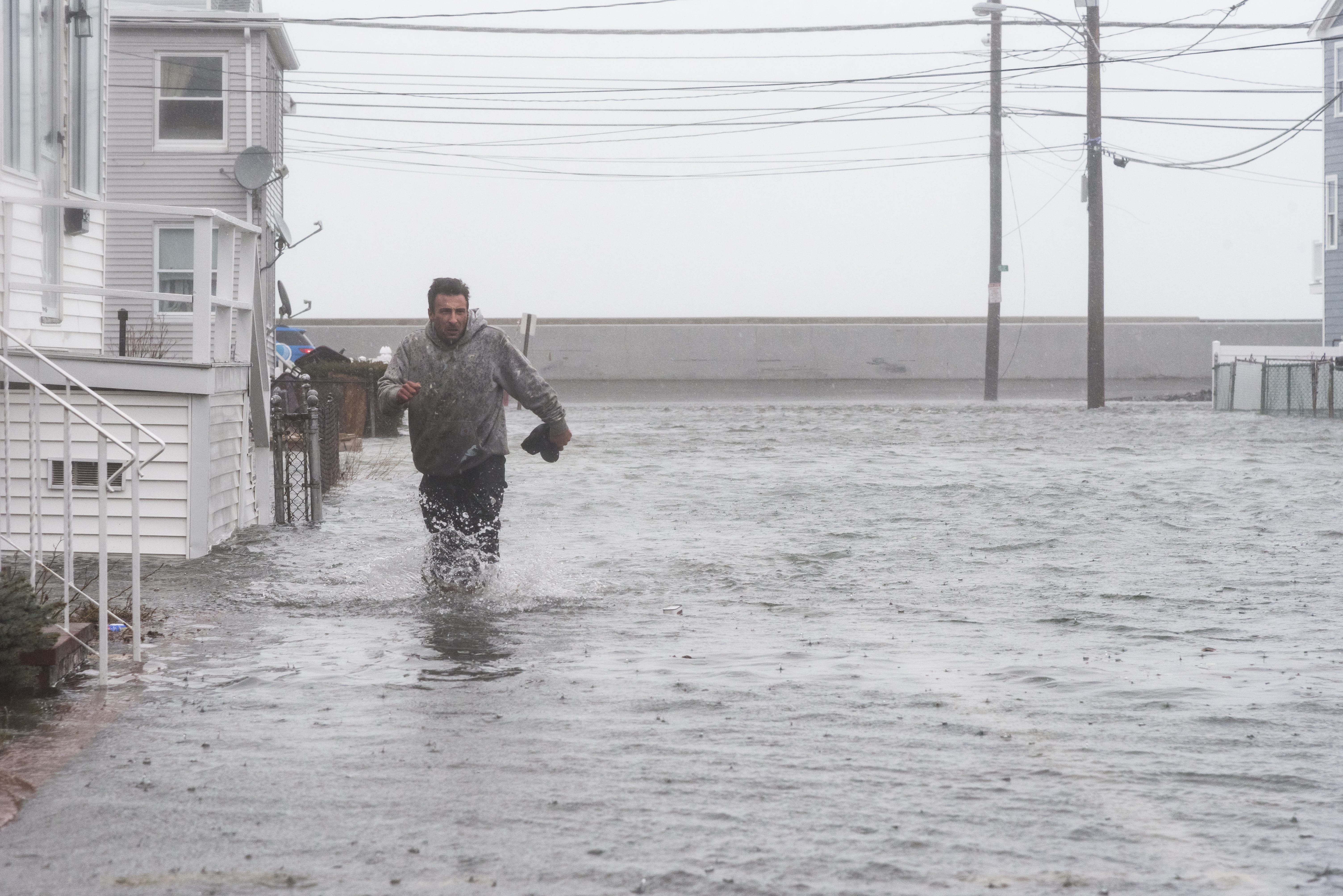 Nick Marazzi of East Boston wades through the flood waters on Pearl Avenue in Revere as he makes his way back to his truck.