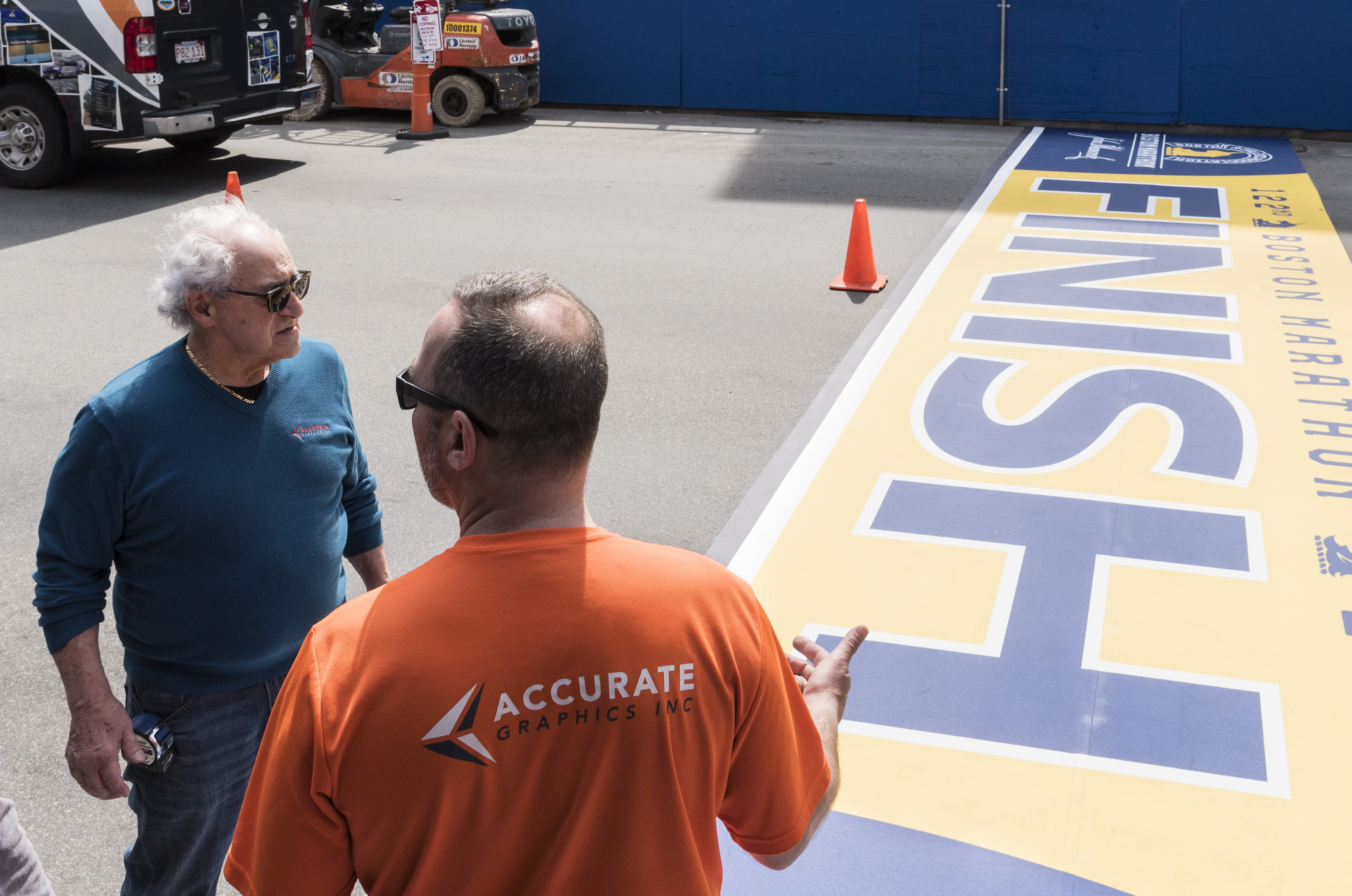 Accurate Graphic Inc. owner Peppy Bolognese, left, and employee Anthony Bisenti speak at the 122nd Boston Marathon finish line, having finished laying it out on Boylston Street in Boston on Thursday.