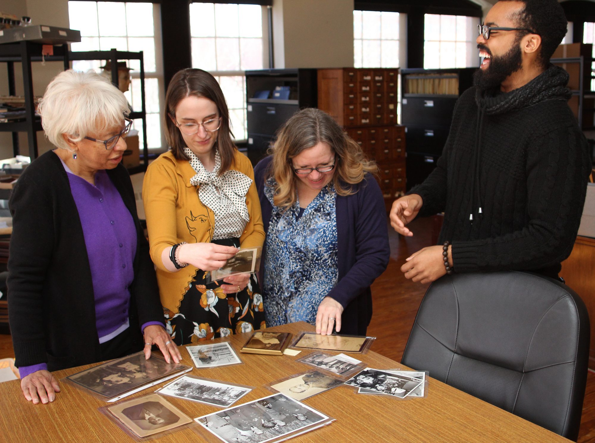 Lynn, Ma. 2/13/19. From left to right: Iris Kimber, Judith Marhsall, Sue Walker, and Richard Valentine look through photographs that will be part of the Untold Stores Exhibit at the Lynn Musuem this summer.