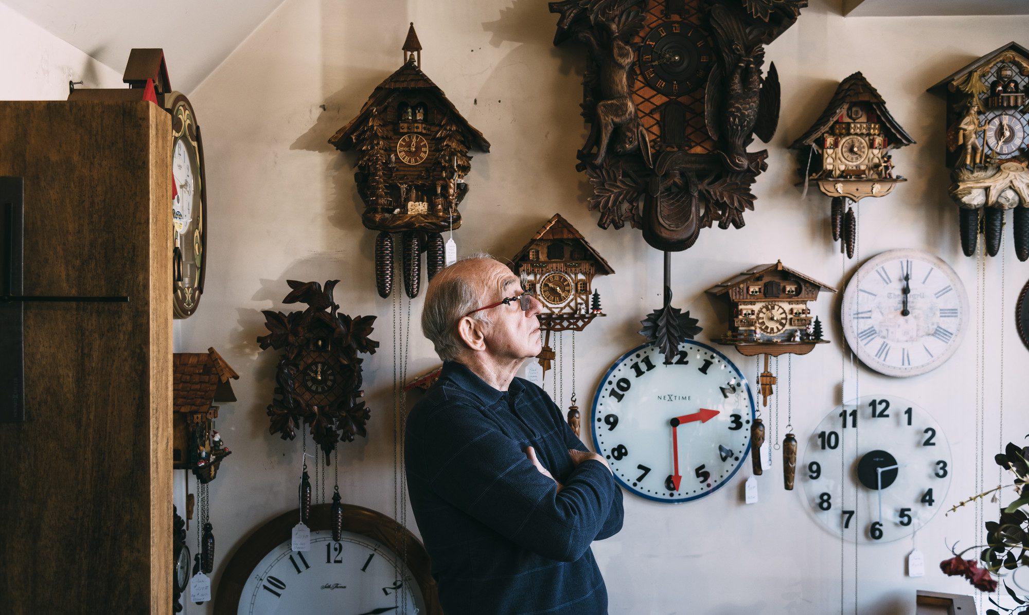 George Phillips, surrounded by clocks, looks out the front window of his shop, Phillips' Clock Shop, in Swampscott.