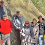 A group of intrepid hikers pose with geologist Nick Federico in front of the Willis Woods Glacial Erratic