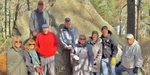 A group of intrepid hikers pose with geologist Nick Federico in front of the Willis Woods Glacial Erratic