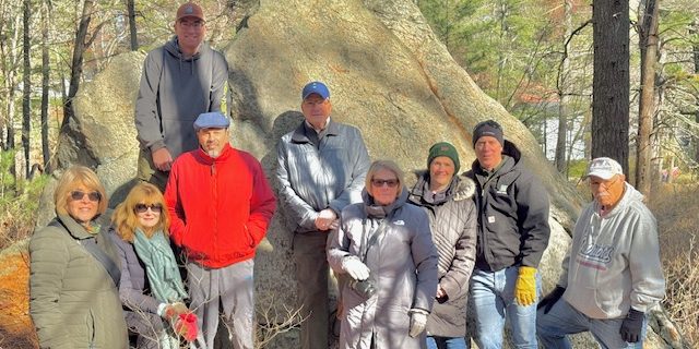 A group of intrepid hikers pose with geologist Nick Federico in front of the Willis Woods Glacial Erratic
